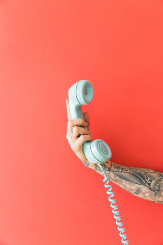 tattooed arm holding a telephone