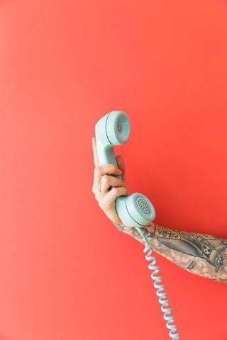 tattooed arm holding a telephone